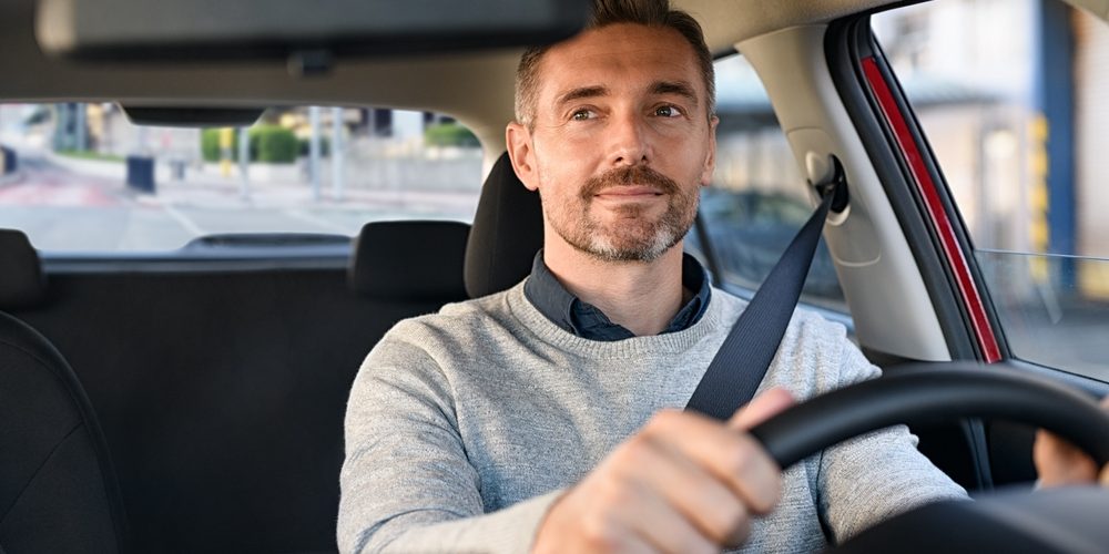 Mid,Adult,Man,Smiling,While,Driving,Car,And,Looking,At