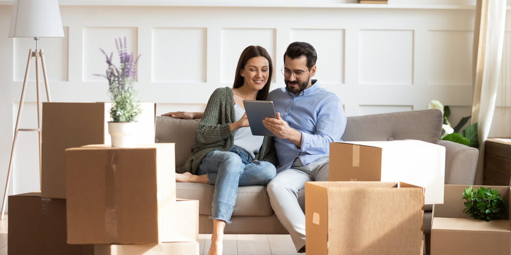 Full,Length,Happy,Family,Sitting,On,Couch,Among,Cardboard,Boxes