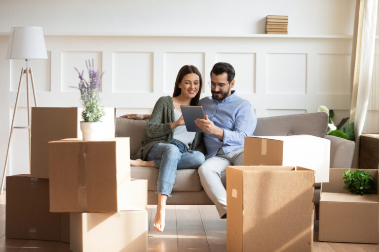 Full,Length,Happy,Family,Sitting,On,Couch,Among,Cardboard,Boxes