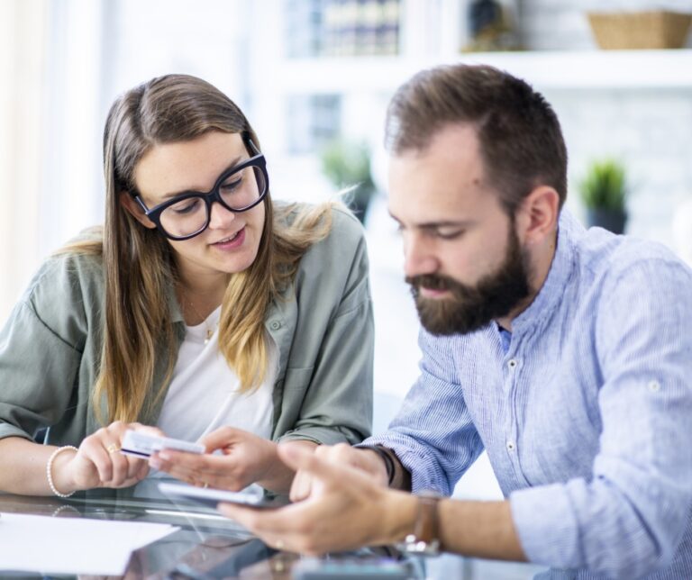 Two people engaged in personal financial planning, likely reviewing expenses or managing a budget